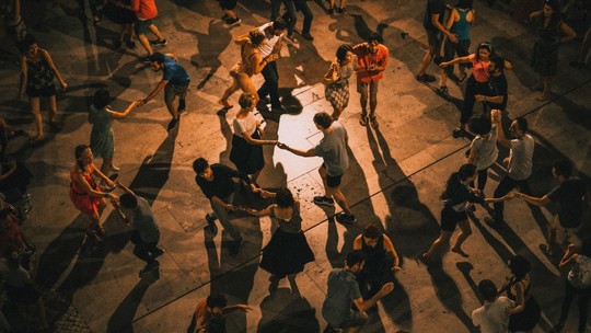 Couples dancing in a large outdoor space during the evening 