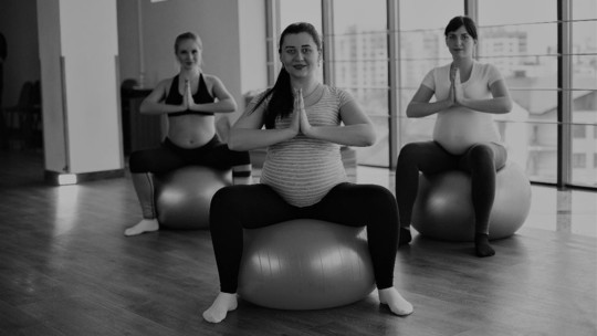 Three pregnant women in an exercise studio, each sitting on a balance ball 