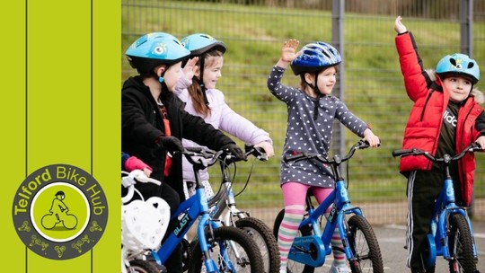 4 happy primary school age children on bikes with helmets. The Telford Bike Hub logo is in the bottom left of the image.