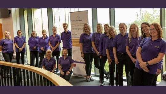 A photo of the Healthy Lifestyles Team in their purple polo shirts by a large window