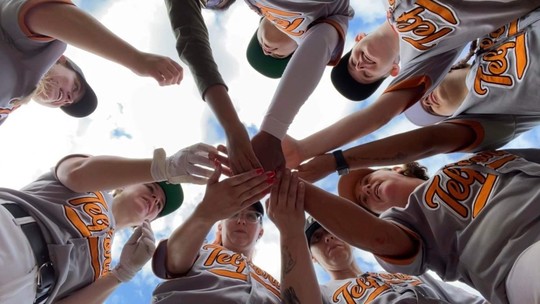 8 women in Telford Giants baseball caps and uniform, in a circle with all hands in