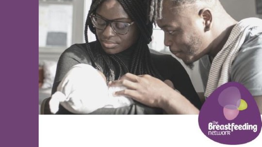 A man and woman look down at their baby, cradled in the woman's arms