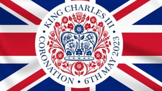 A British flag with a round image in the centre showing a crown surrounded by daffodils, thistles, shamrocks and Tudor roses