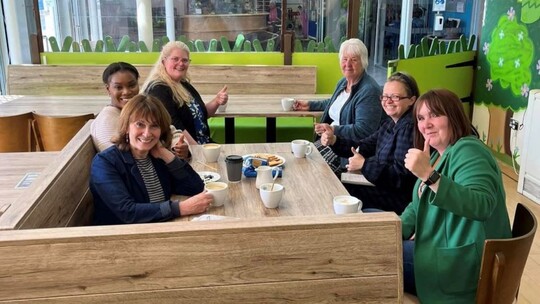 Photo shows 6 women sitting around a table in a light and airy cafe space. The photo was taken at the first menopause chat in June. 