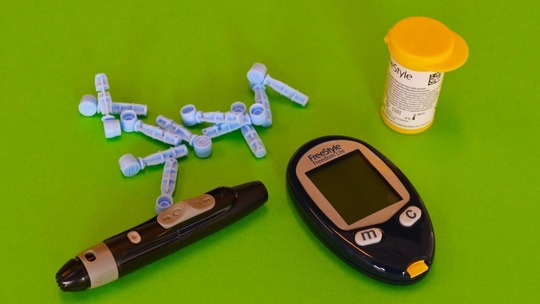 Equipment needed to manage type 2 diabetes laid out on a green surface.