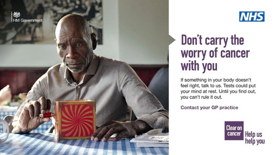 A worried looking man sits at a cafe table with an unopened red and gold jack in the box. His hand is on the handle.