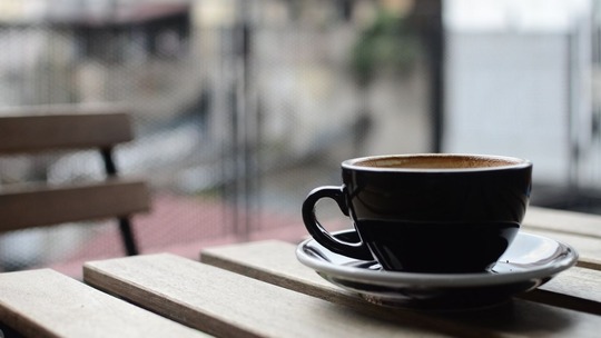 Close up photo of a dark brown tea cup on a cafe table