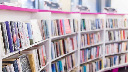 A close up of a curved bank of white library shelves filled with books