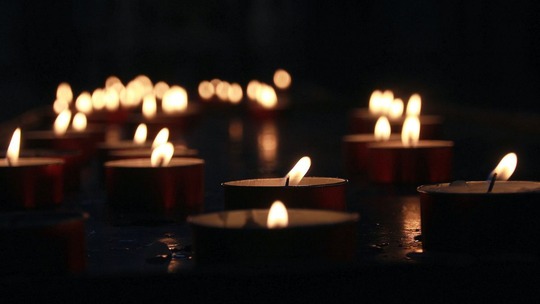 A crowd of lit tealights in a dark space