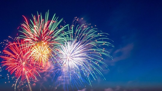 Red and blue starburst fireworks in a deep blue sky