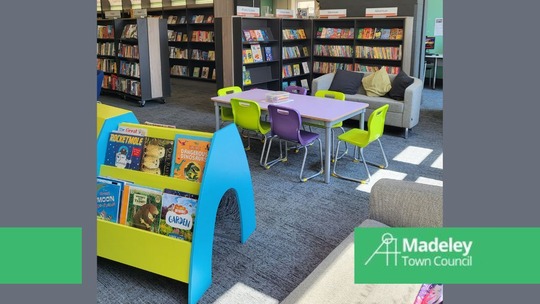A photo of the colourful shelves and seats in the children's area of Madeley Community Library. Madeley Town Council logo bottom right.