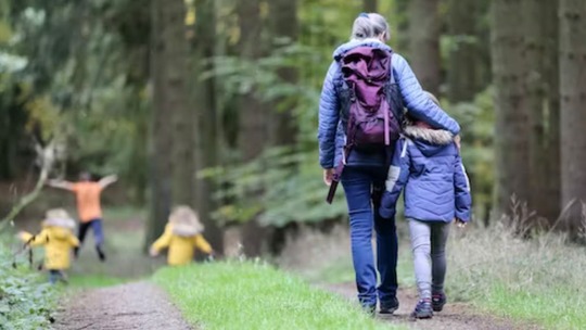 A mother and young son in the foreground. and 3 more children in the distance, all on a woodland path.