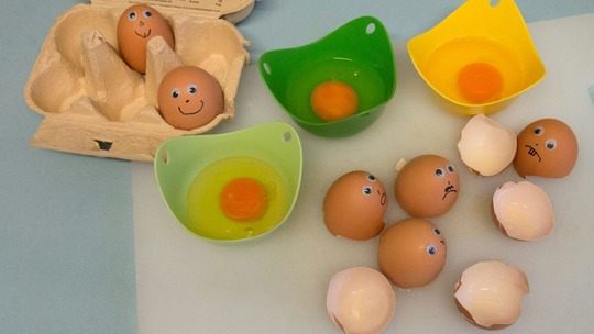 Eggs with googly eyes and mouths drawn on them. Some are broken, some are still whole.