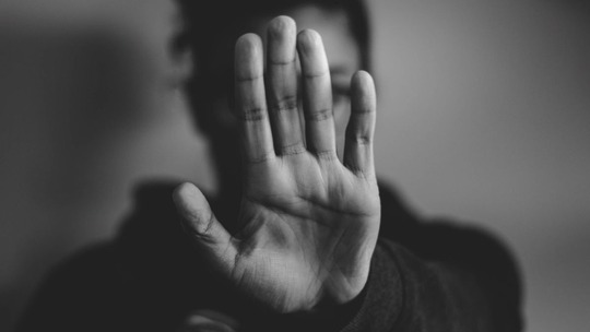 Black and white photo of a woman with her hand up in a 'stop' gesture.