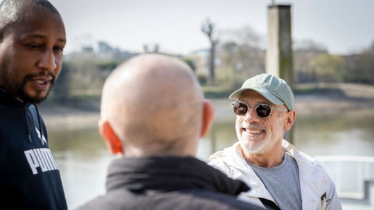 3 men standing in an outdoor space smiling and chatting.