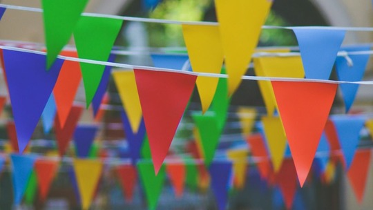Yellow, blue, red and green bunting strung back and forth in an outdoor space