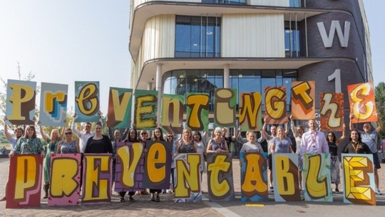 A group of Telford and Wrekin staff outside Southwater 1 building holding up signs that spell out "preventing the preventable"