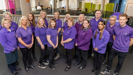 Group photo of the 16 Healthy Lifestyles Advisors, all wearing their purple polo shirts.