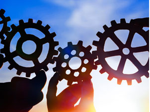 close up of cogs with a colourful sunset in the background