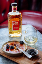 glass of Aberfalls Single Malt whiskey next to the bottle and a creme brule on a table