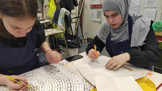 Two students create designs at a workshop