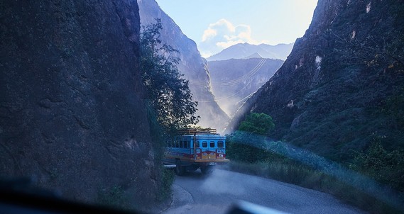 A bus disappears round a bend on a misty mountain road. Image by Jake Green