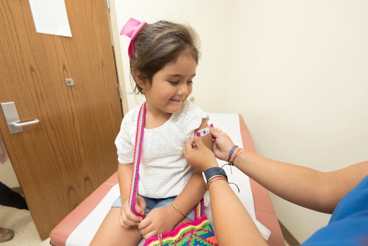 A nurse puts a plaster on the arm of a child after their vaccination