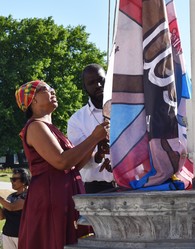 Two people raise the Windrush flag in Fellowship Square 2022