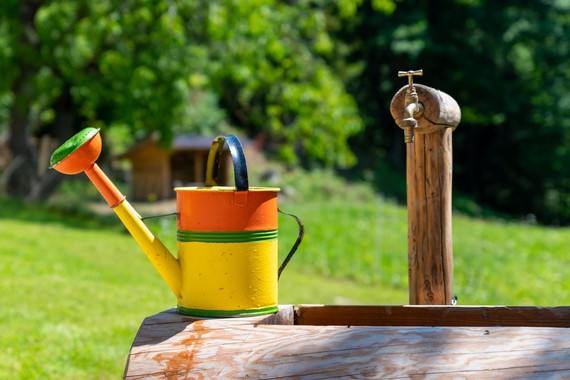 Watering can in front of an outdoor tap