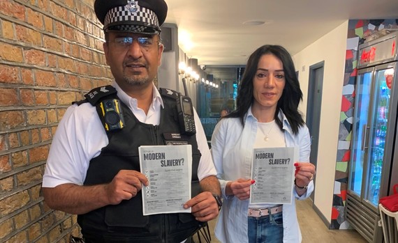 A police officer and residents pose with information leaflets about modern slavery