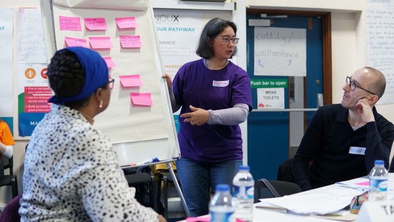 People in a classroom looking at a flip chart with Post It notes on