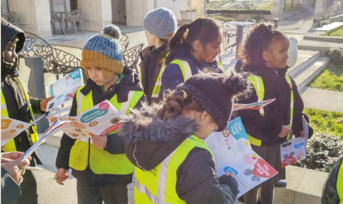 Pupils in high vis jackets explore Fellowship Square as a group