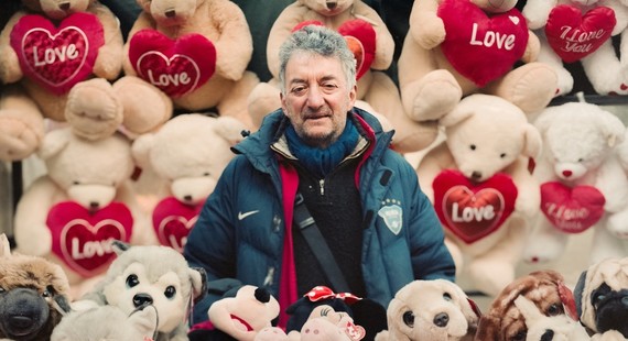 A market trader surrounded by teddy bears and red hearts