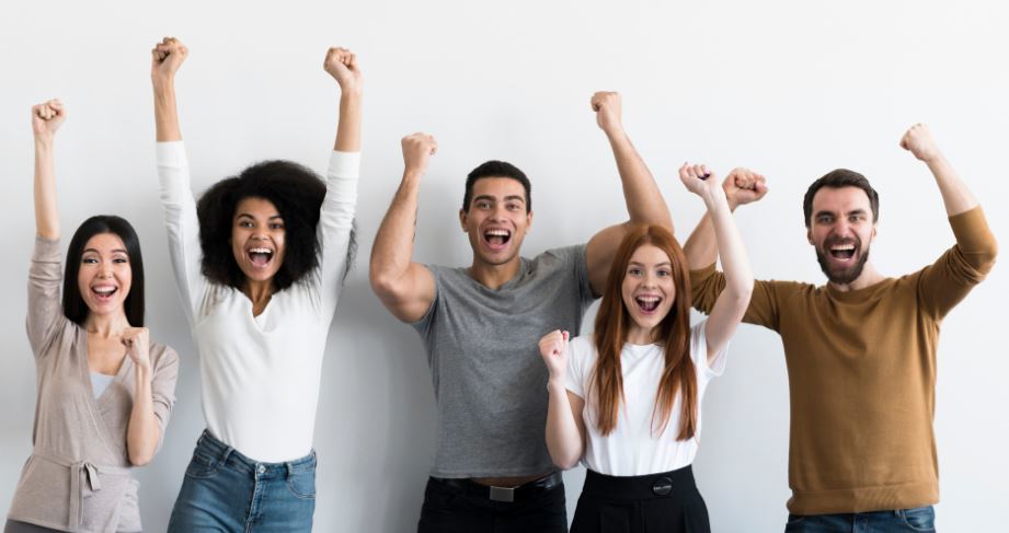 a line of people wave their arms in the air with joy for Dry January