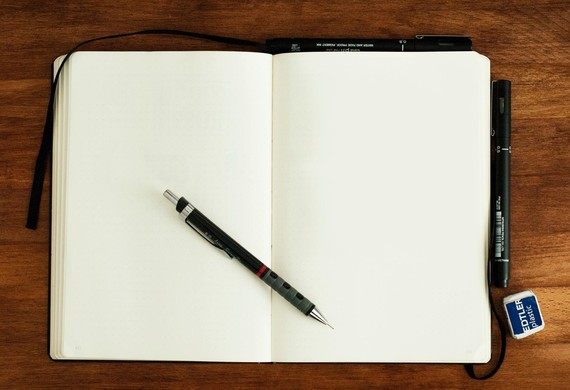 A pen lies on an open notebook on a table 