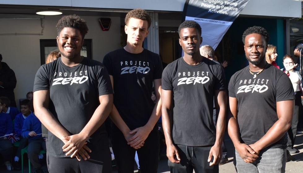 Four young people wearing Project Zero T-shirts stand outside
