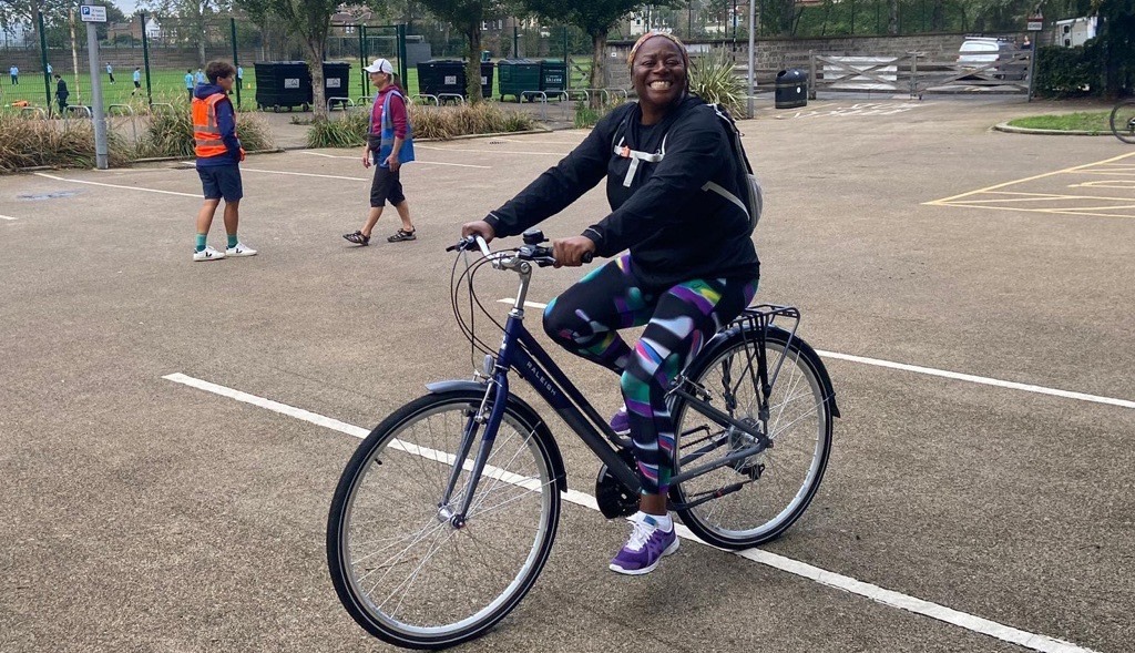 A cyclist in brightly coloured leggings smiles from the back of a bike