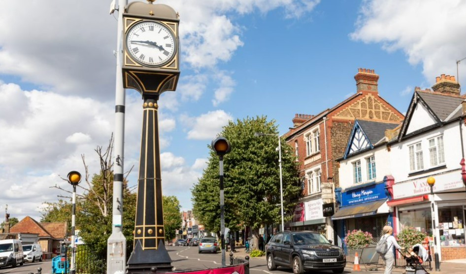 The clock in Highams Park town centre with shops and trees behind