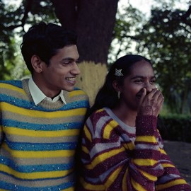 Two smiling people wearing striped jumpers