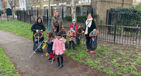 A group of adults and children with litter picking sticks and bin bags