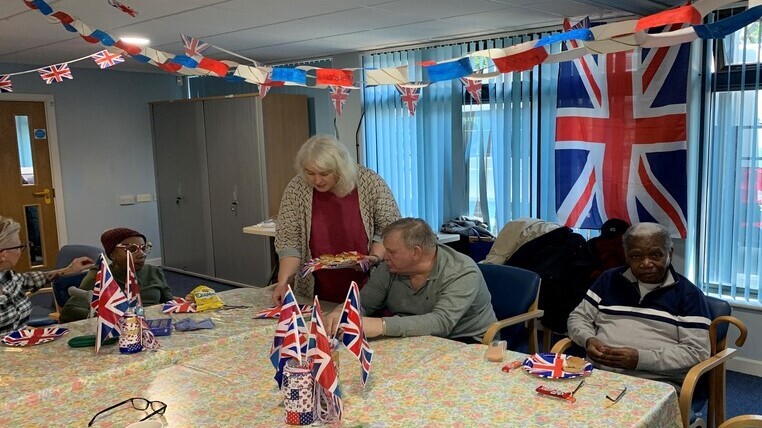 Cllr Louise Mitchell serves some of the guests at a table covered in Union flags, with bunting overhead