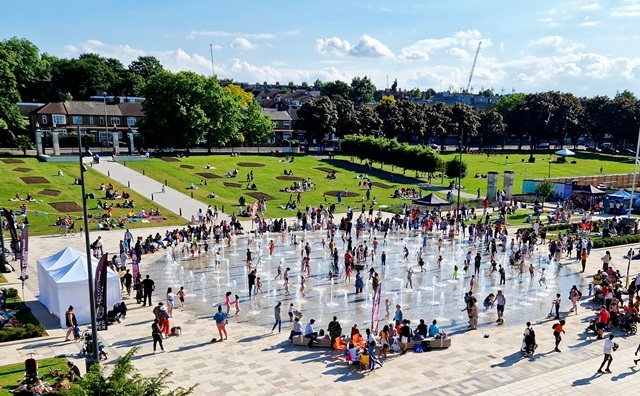 Crowds enjoy the sun and fountains in Fellowship Square