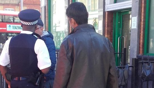 A police officer talks to a man at Baker's Arms in Leyton. Another man looks on