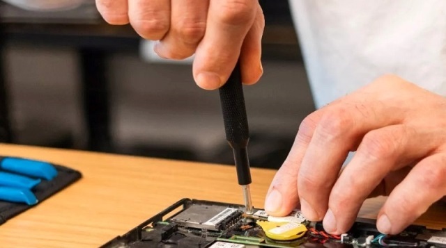 Close up on hands using a screwdriver to repair an electrical board