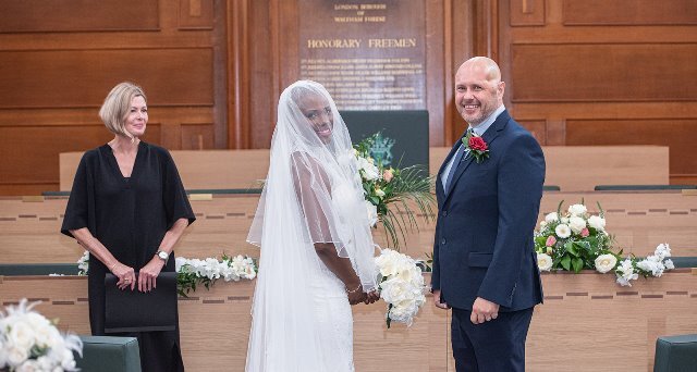A bride and groom pose for photos in Waltham Forest Council Chamber