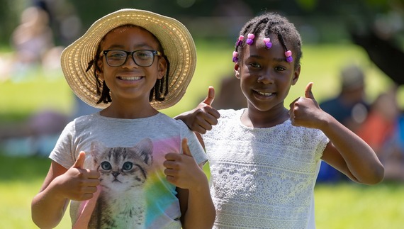 Two girls smile and give thumbs up signs at the Hive