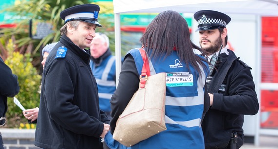 Two police officers and a council officer wearing a Safe Streets high vis vest chat outside