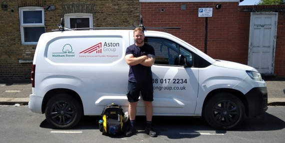 A gas safety engineer stands with arms folded across their chest in front of an Aston Group and Waltham Forest Council van