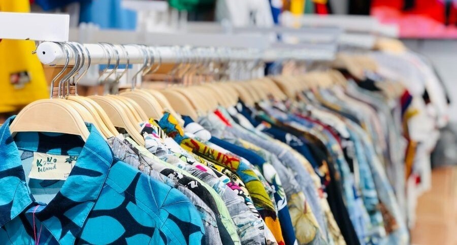 Rails of brightly coloured pre-loved shirts hanging in a shop