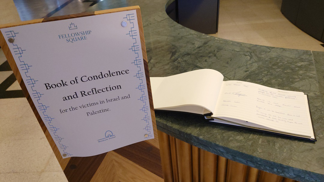 A sign in Fellowship Square directing residents to the book of condolence and reflection on the desk next to it